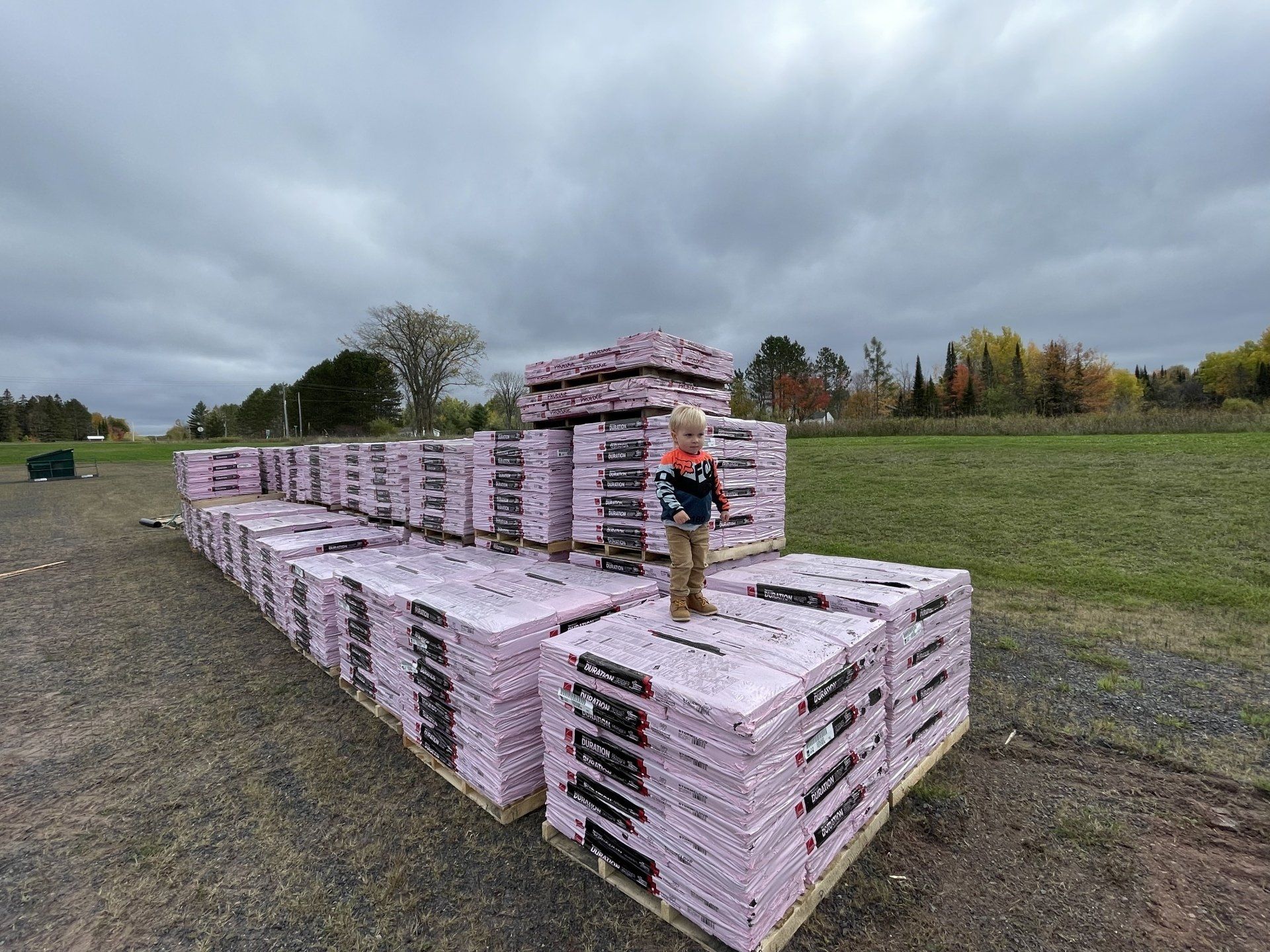 A person is standing in front of a large stack of bricks.
