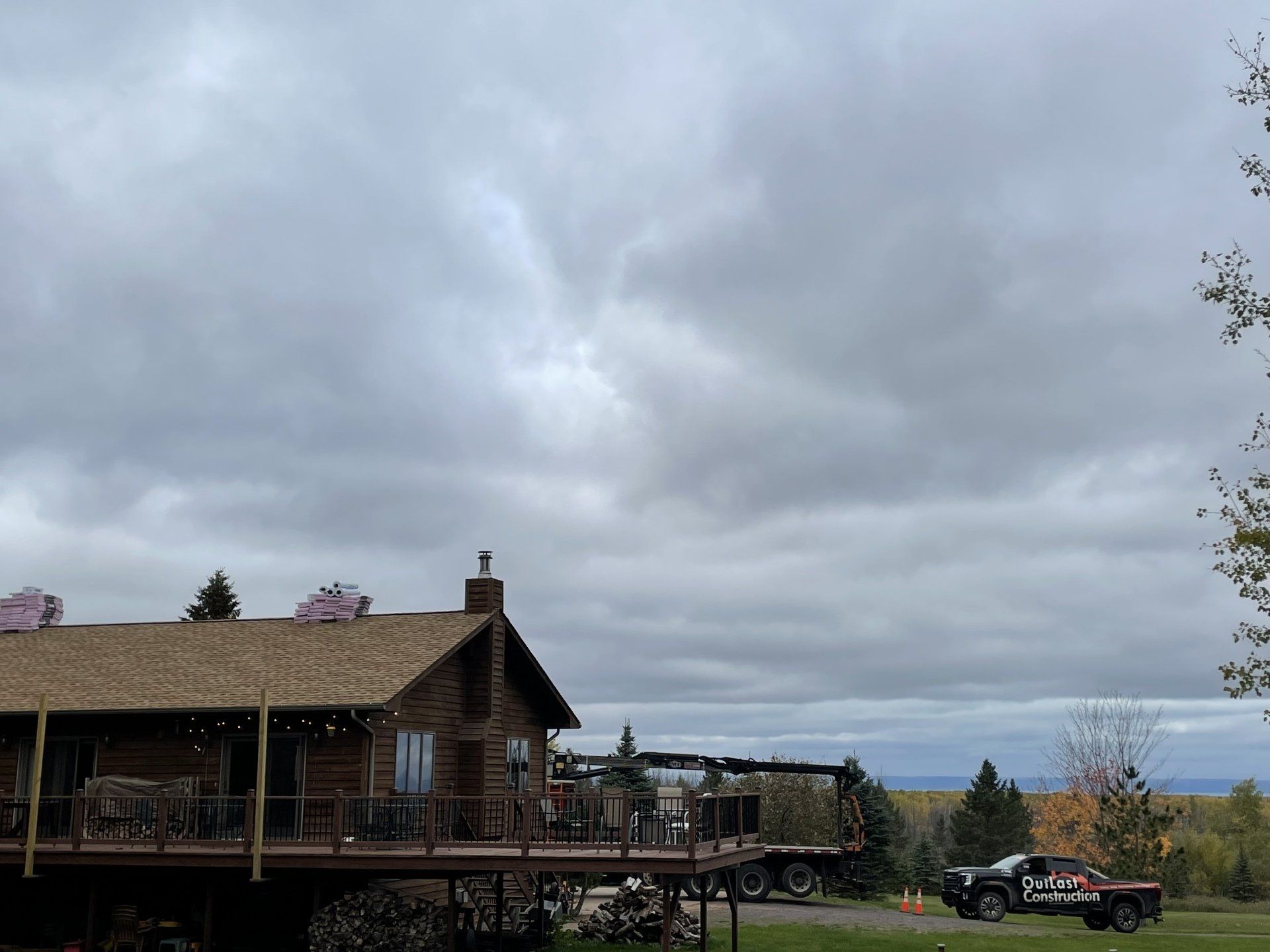 A large log cabin with a large deck and a truck parked in front of it.