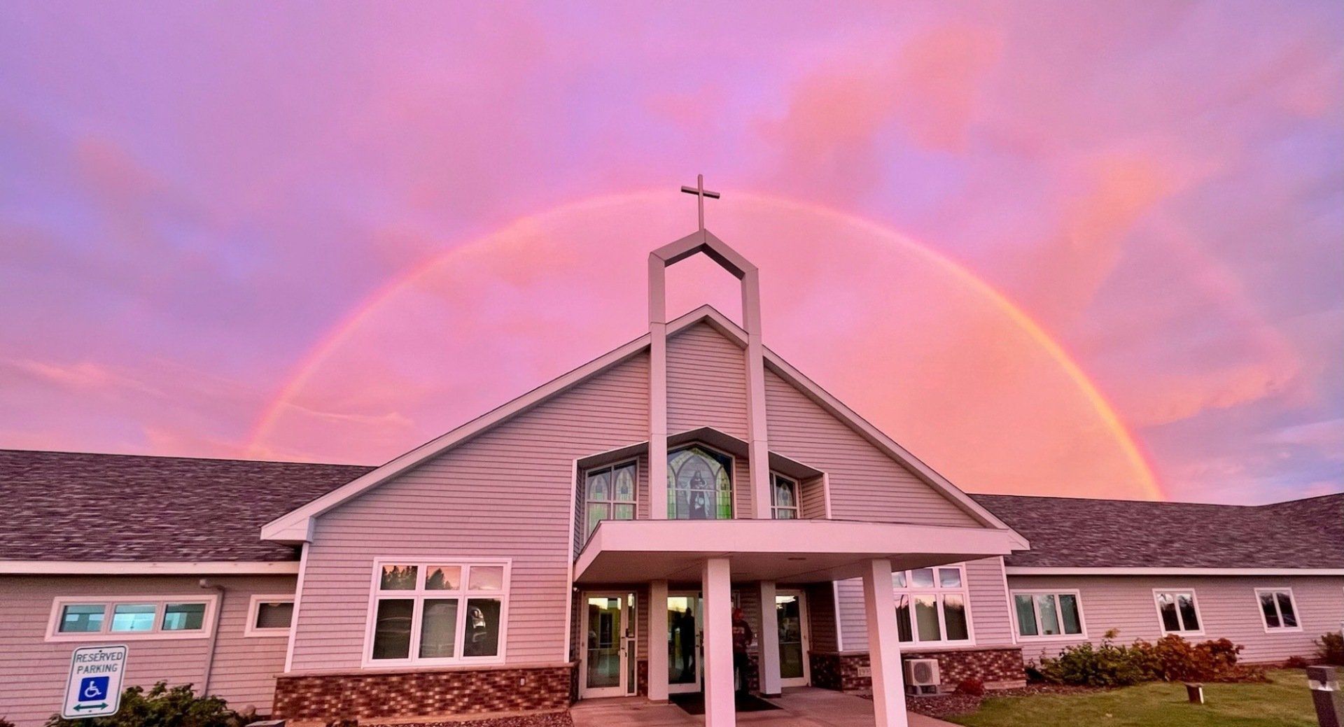 A church with a rainbow in the sky above it.