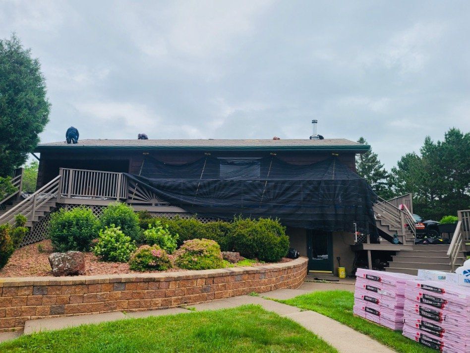 A large house with a black tarp on the roof is being remodeled.
