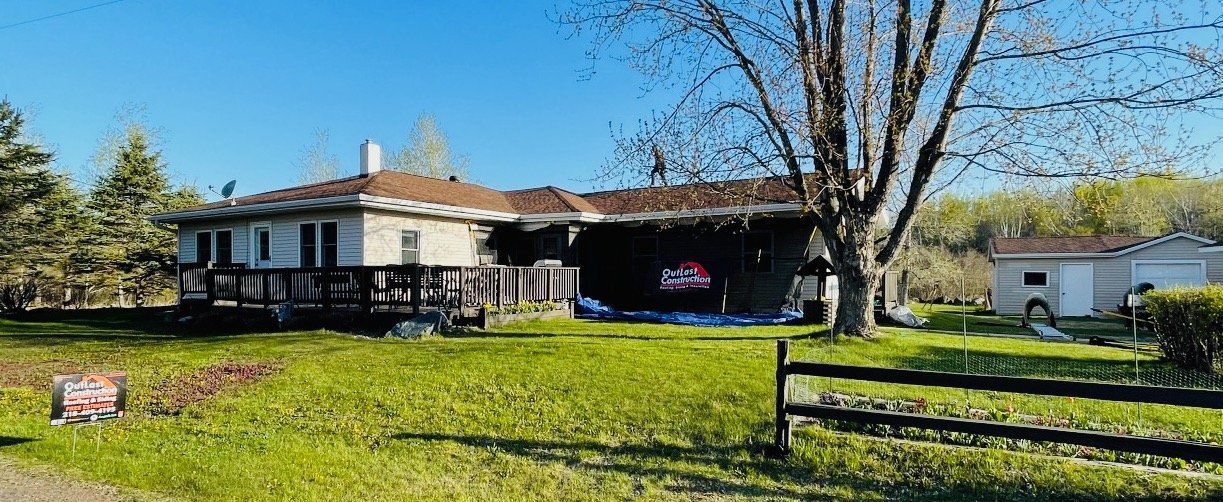 A house with a fence in front of it is sitting on top of a lush green field.