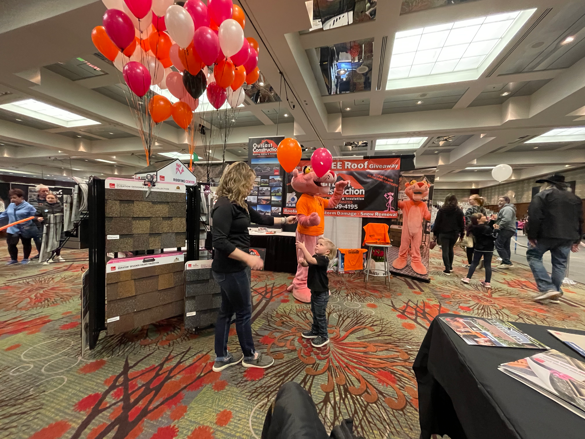 A group of people are standing in a room with balloons hanging from the ceiling.