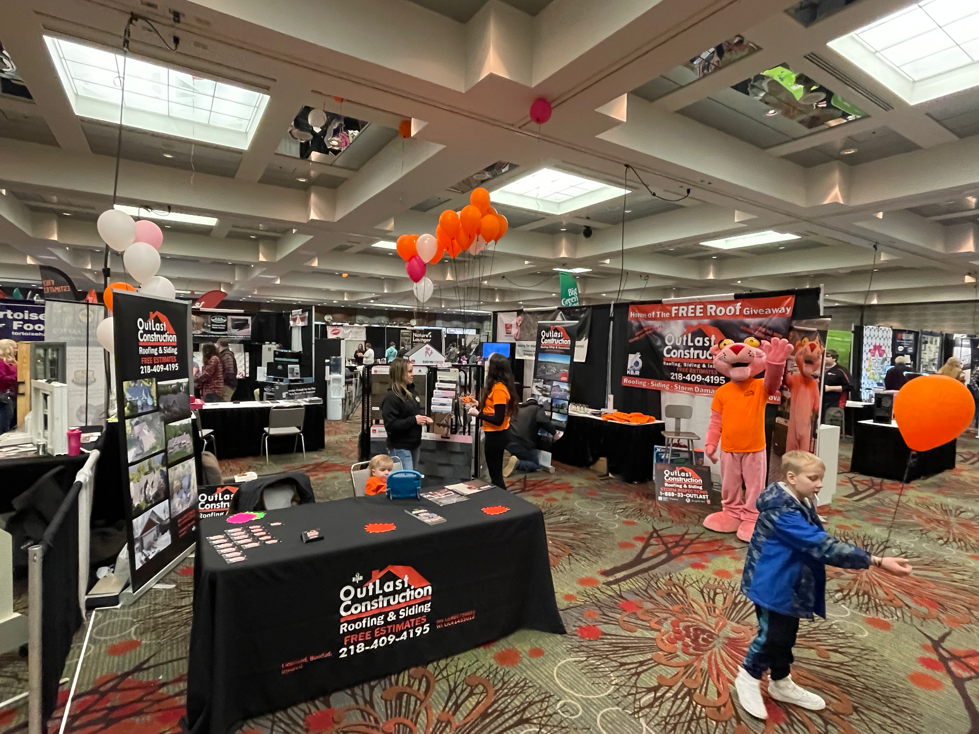 A little boy is standing in front of a table at a convention.