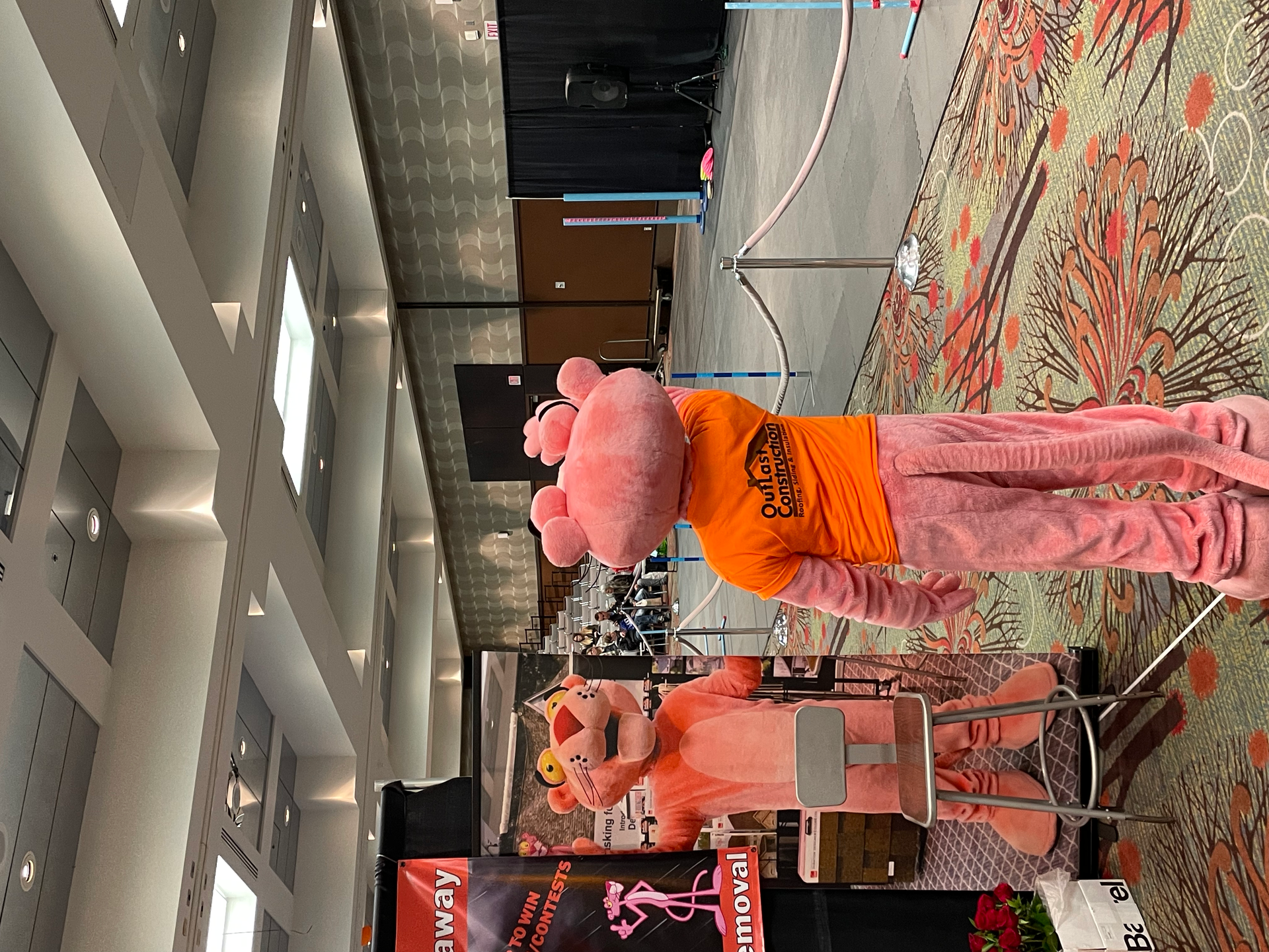 Two pink panther mascots are standing next to each other in a room.