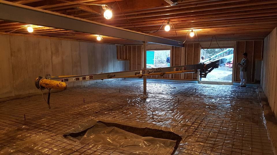 Basement construction in progress: rebar, plastic sheeting, exposed framing, open doorway, and a person.