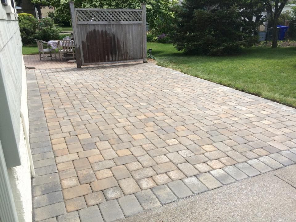Brick patio with wooden fence and green grass.