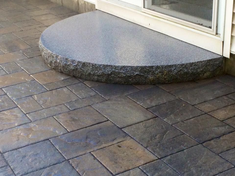 Stone patio with a half-circle step in front of a sliding glass door.