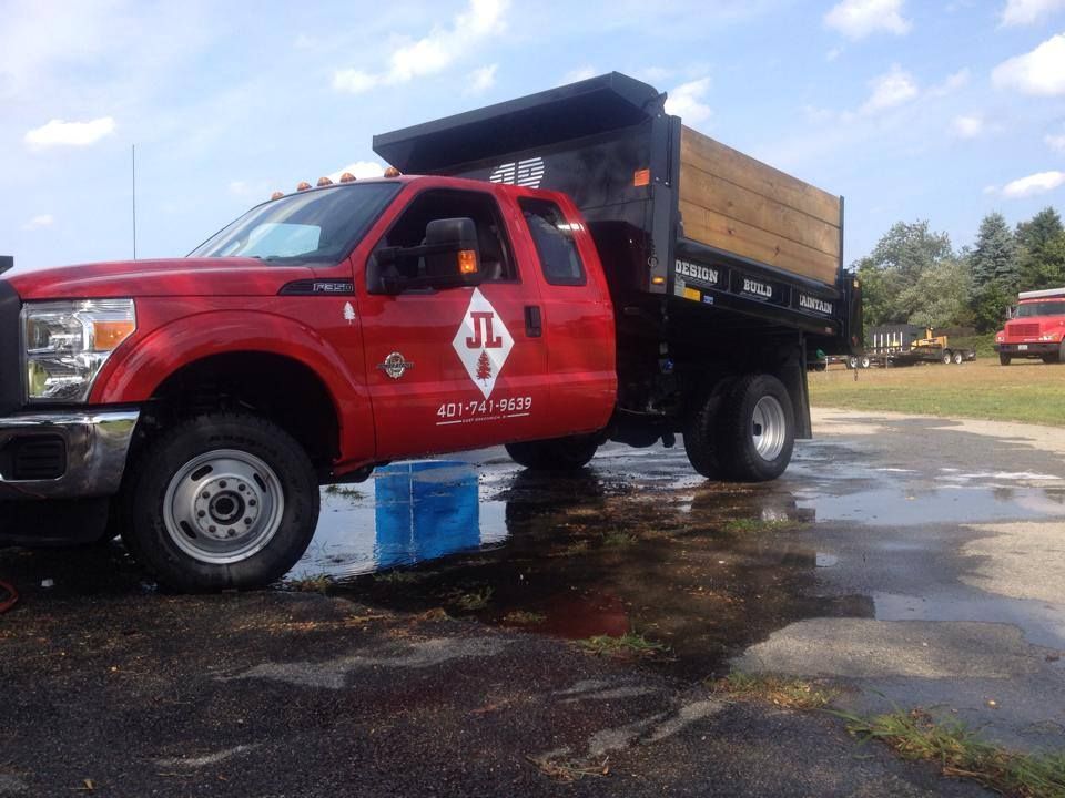 Red dump truck parked on a wet surface with a blue block under the front tire.