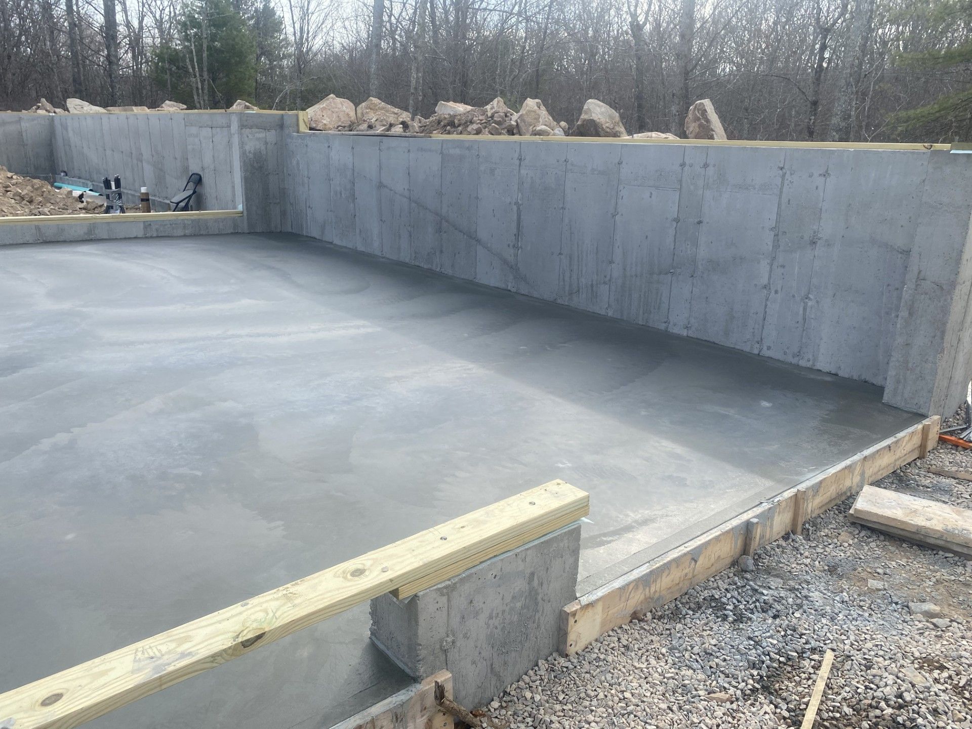 Concrete foundation walls and floor. Newly poured, light gray concrete, unfinished construction outdoors.