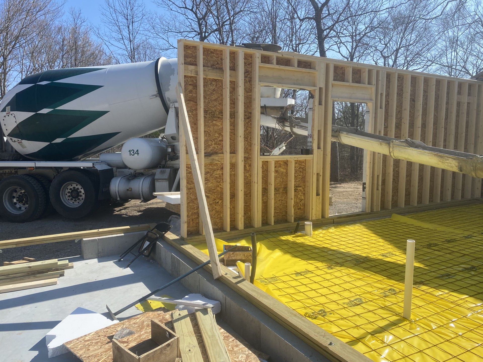Cement truck pouring concrete into a wooden structure under construction on a sunny day.