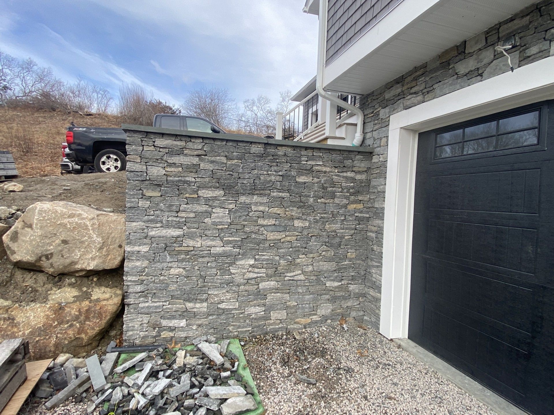Stone retaining wall next to a garage, a truck parked above.