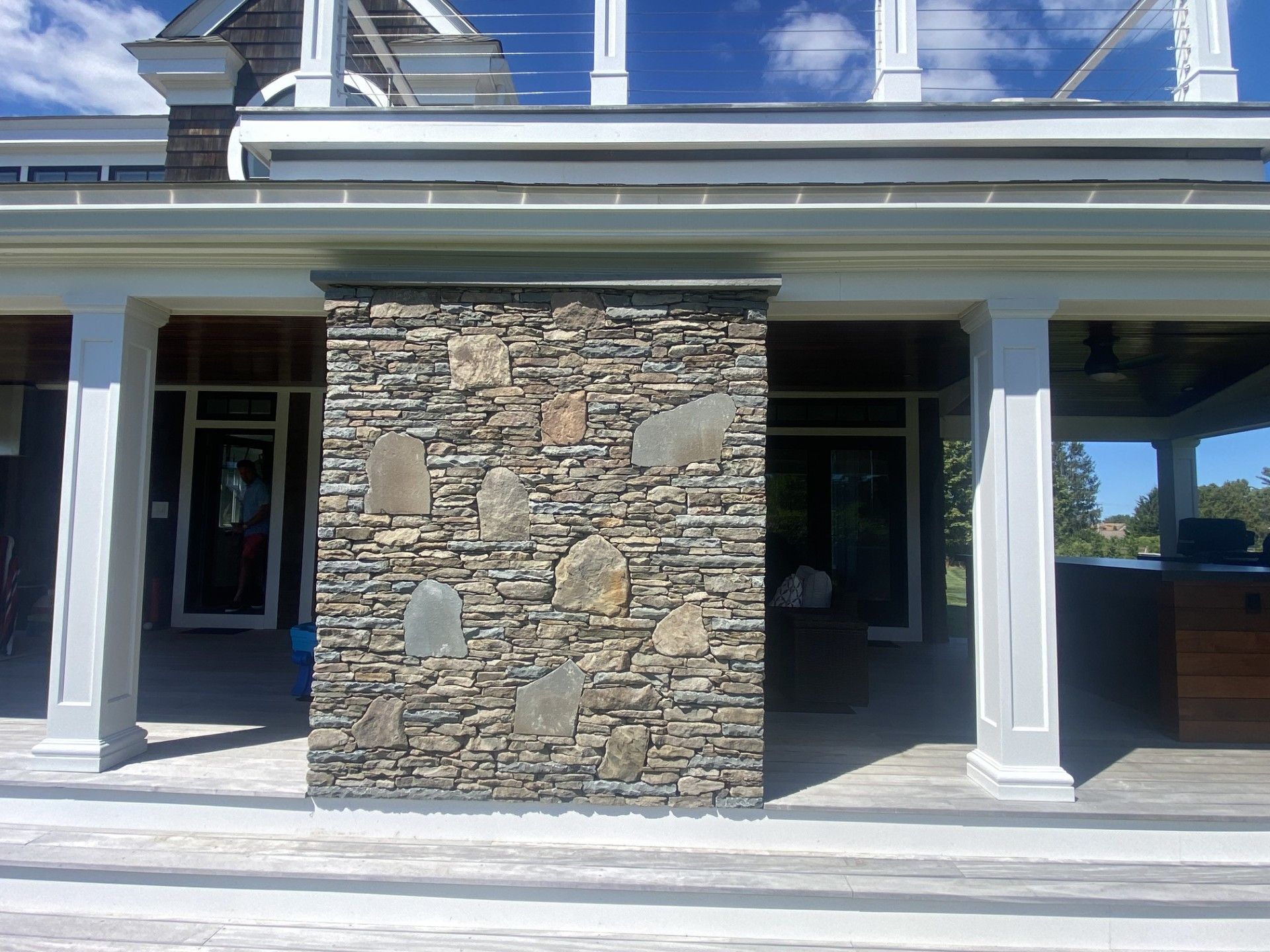 Stone pillar supporting a porch roof with white columns. Doors visible in background under the porch.