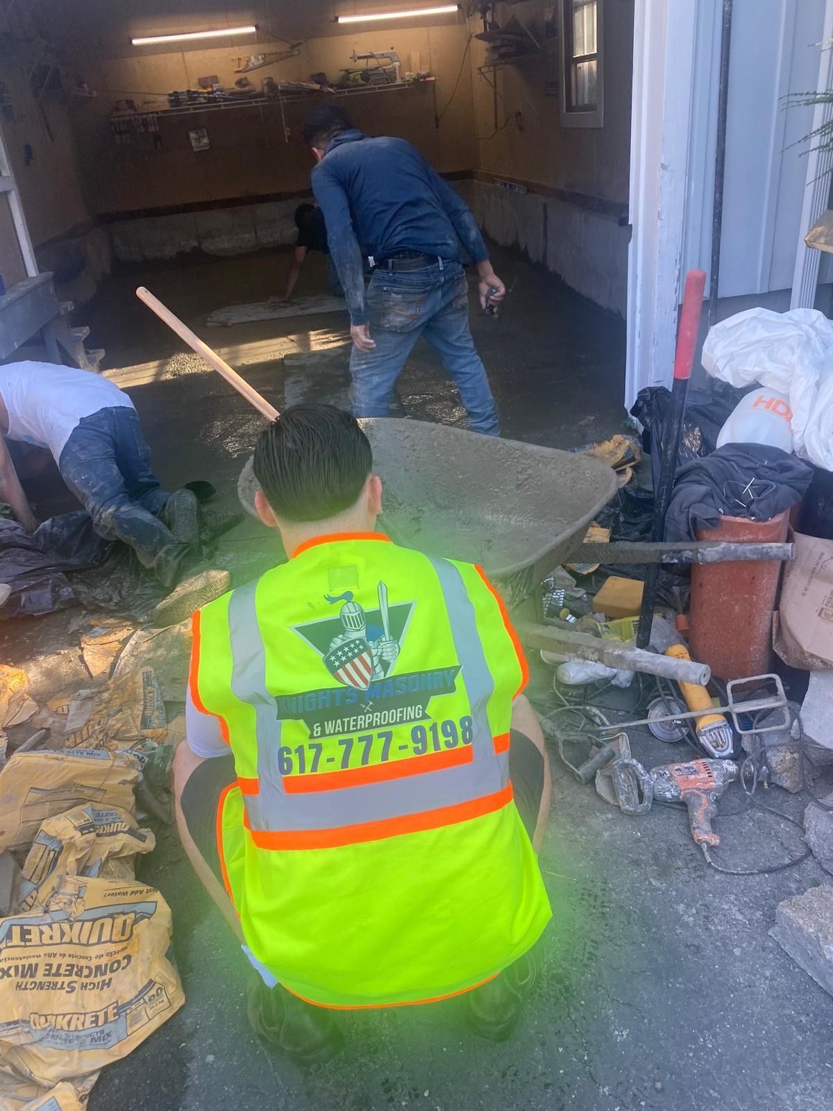 Construction workers are pouring concrete in a garage.