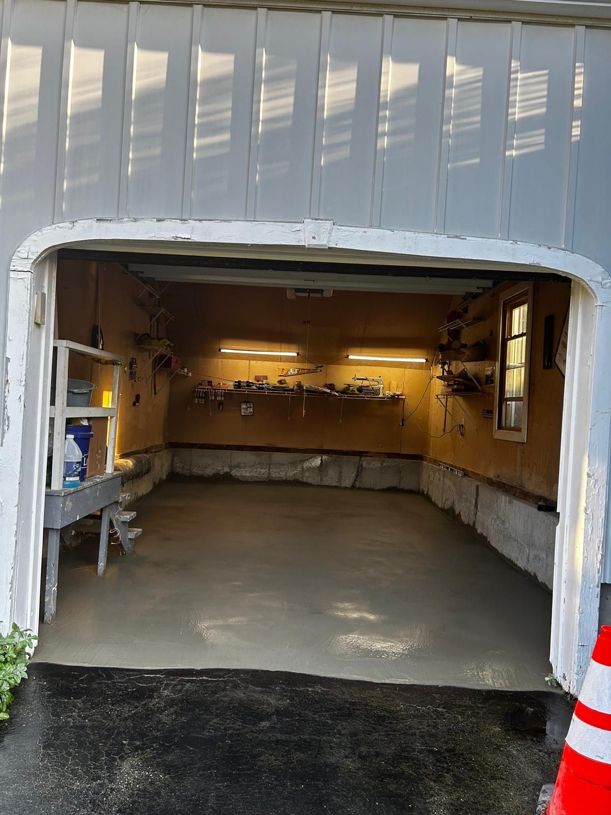 Garage interior with new gray concrete floor; work area with shelves, lights.