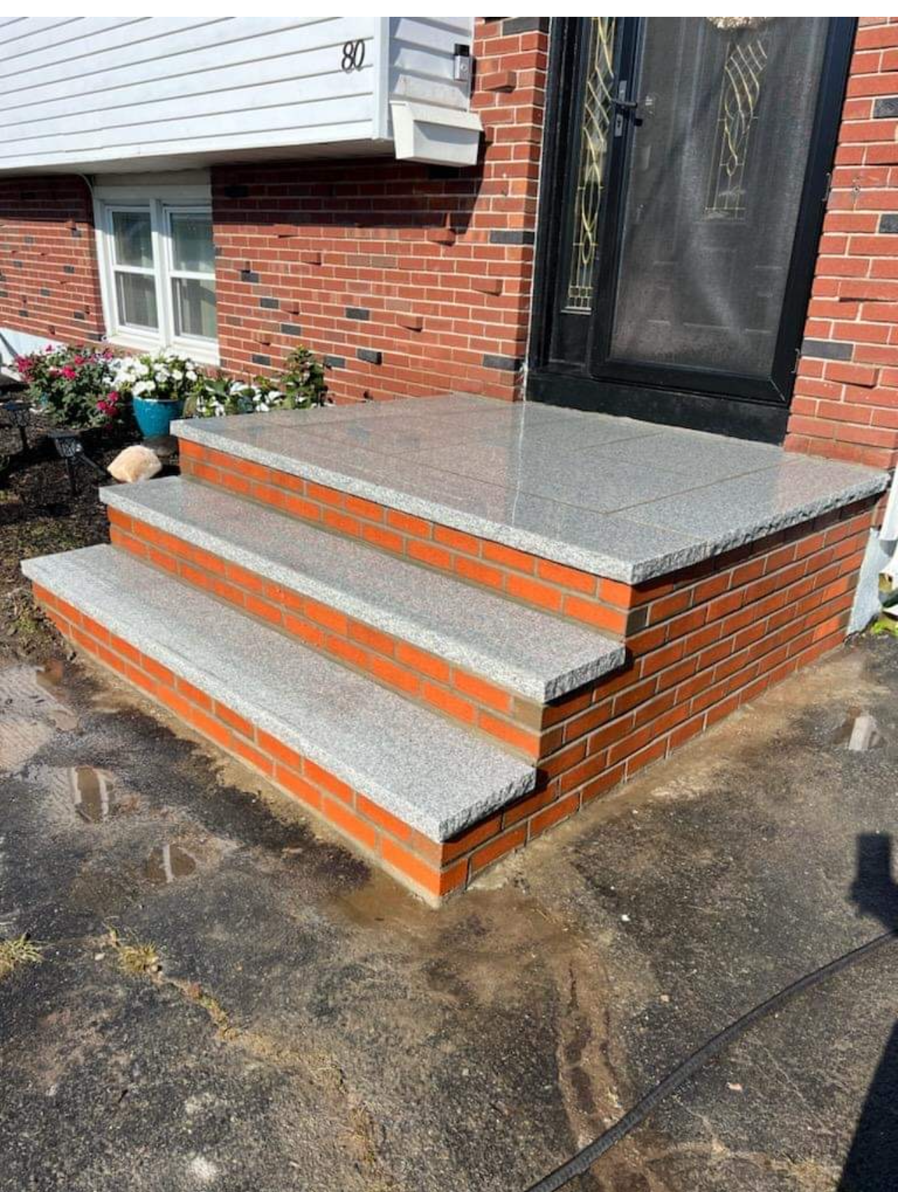 Brick steps with gray stone treads leading to a red brick home's front door.
