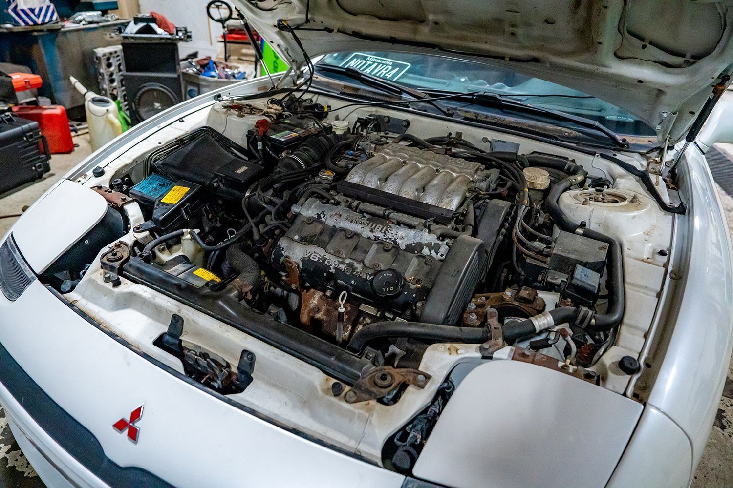 White Mitsubishi sports car engine bay open for repair.