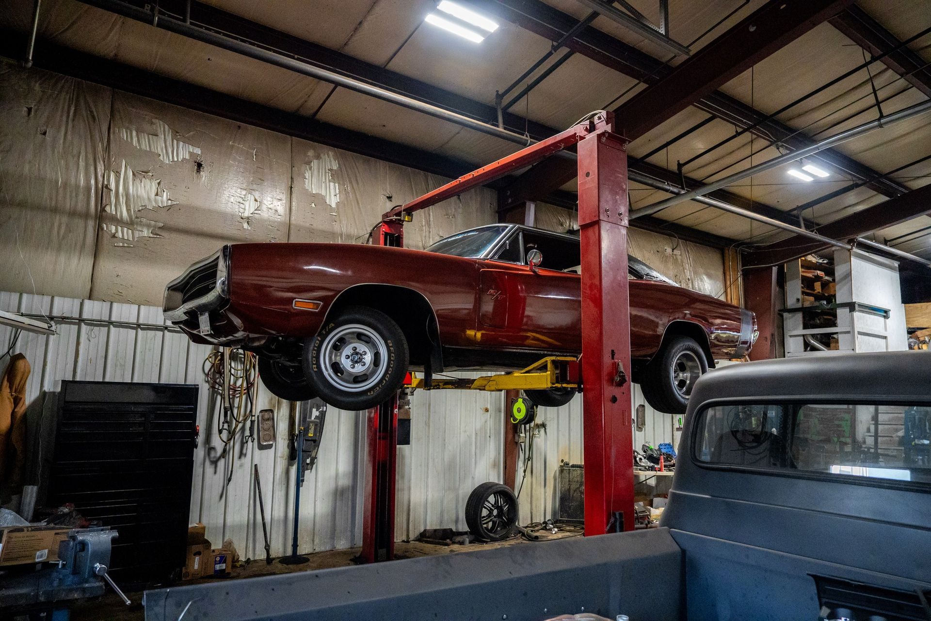 Red classic car raised on a lift in a garage.