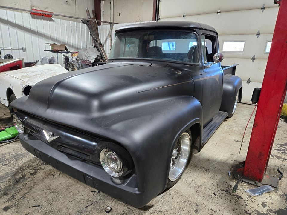 Matte black vintage Ford pickup truck in a garage.