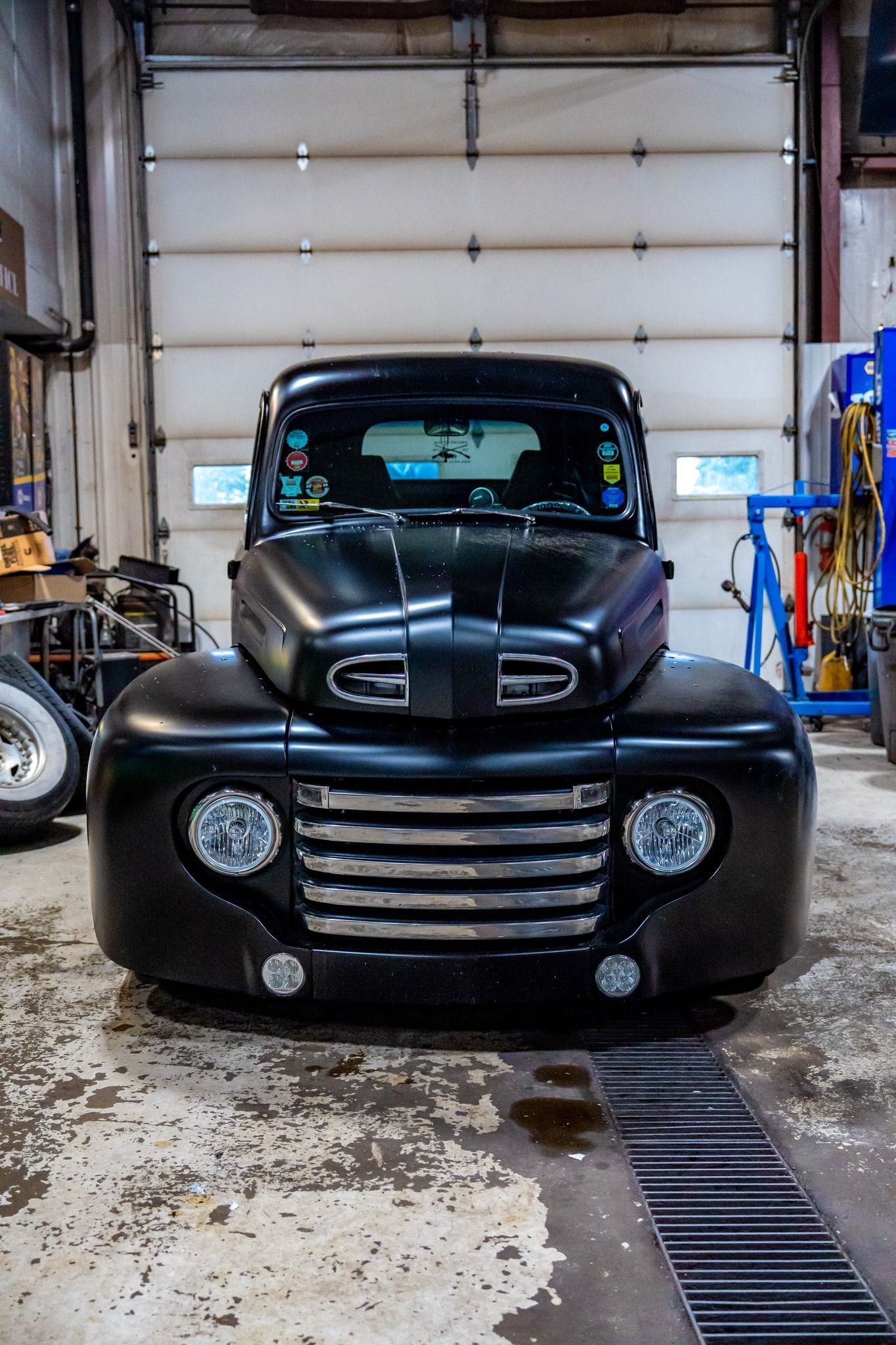 Black Ford pickup truck in a garage, facing forward.