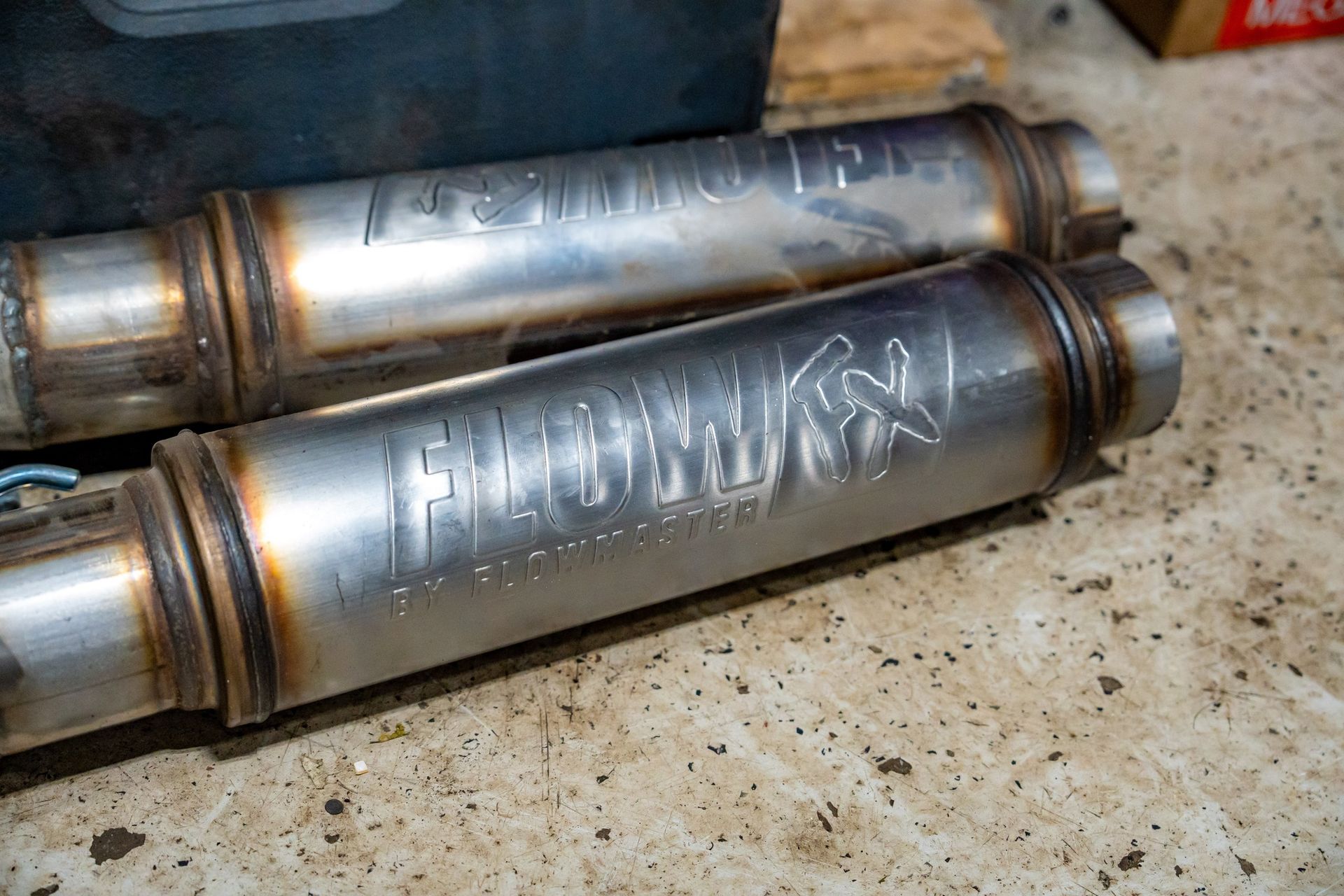 Two stainless steel Flowmaster mufflers, welded and bearing the brand name.
