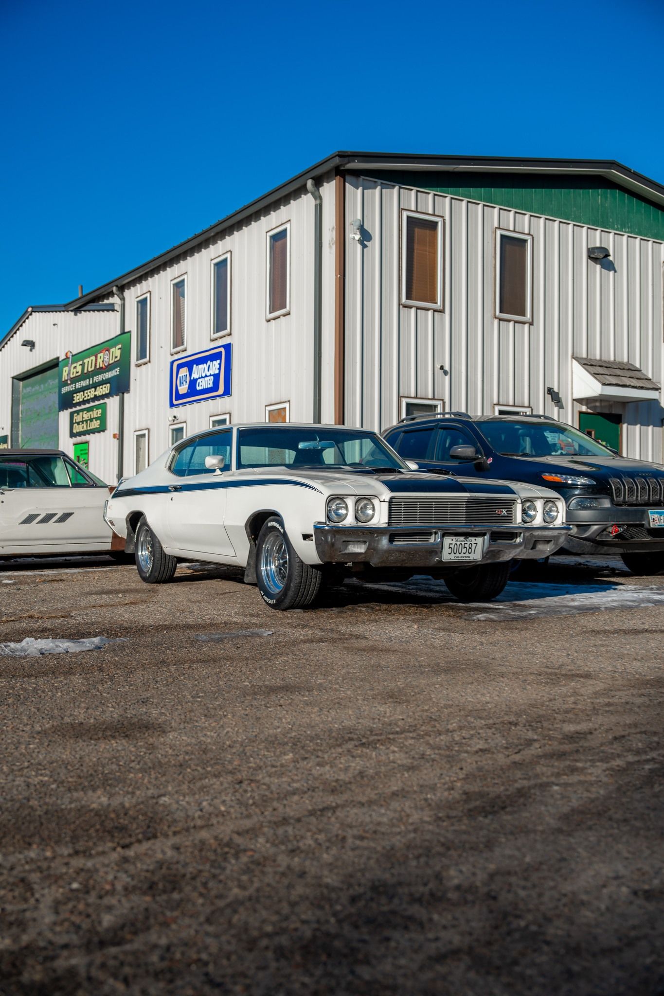 White classic car parked outside a building with a blue sky.
