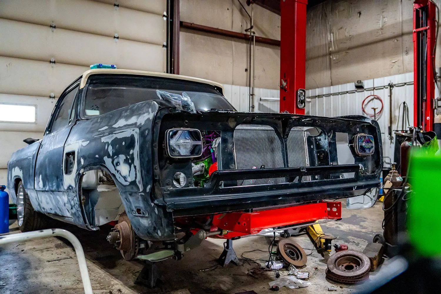 Dodge truck frame in a repair shop; body partially removed, black and gray, on a red support, being worked on.