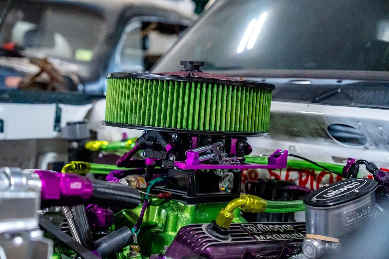 Brightly colored engine with green filter, purple details, and gold lines. Car repair setting.