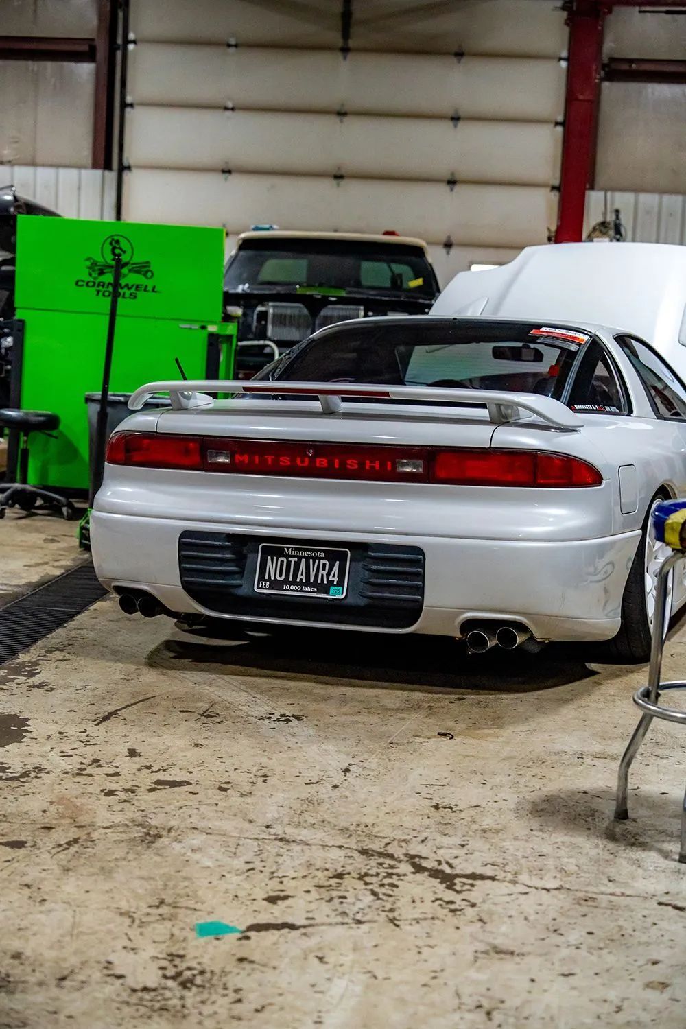 Rear view of a silver Mitsubishi 3000GT in a garage with a license plate that says 