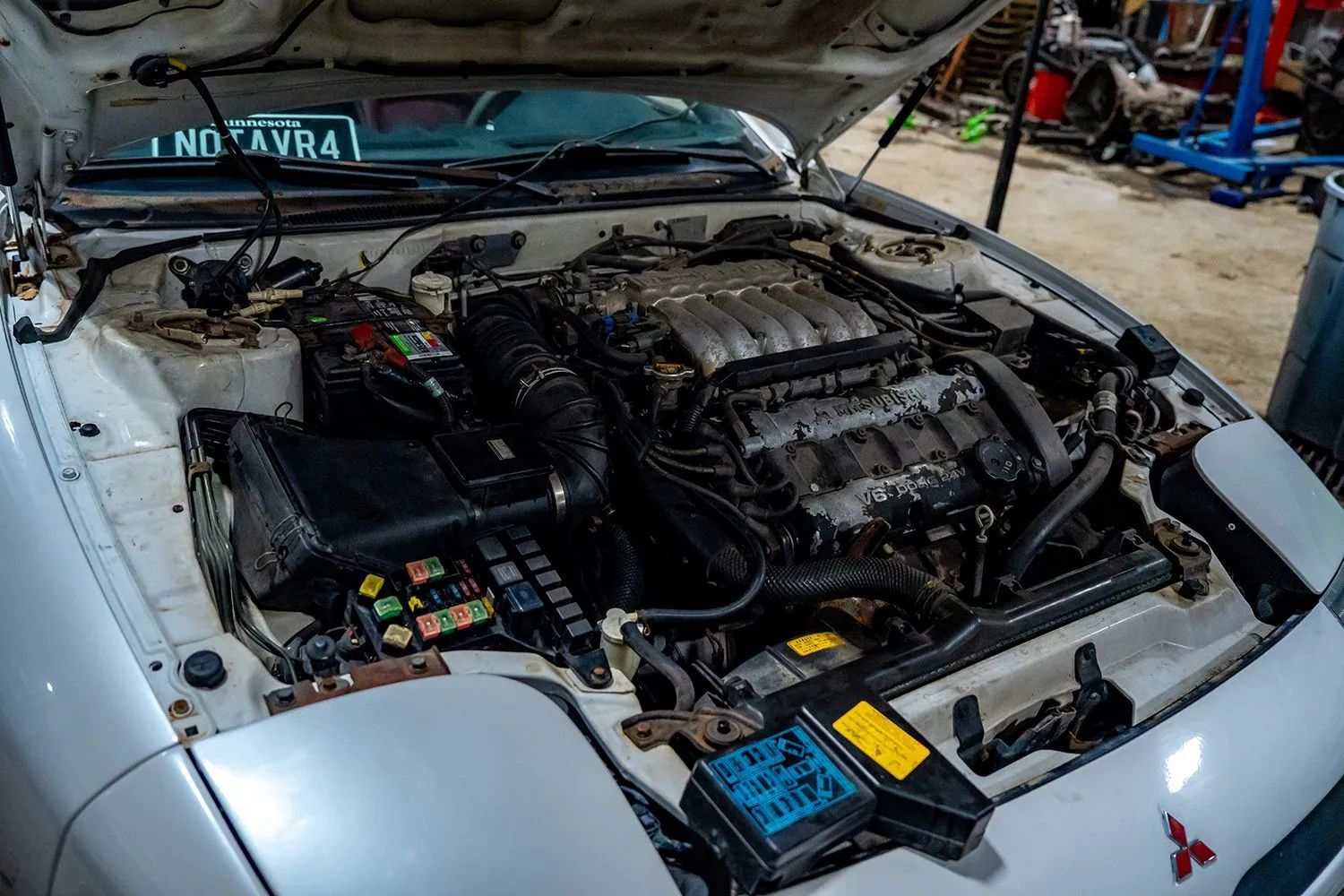 Car engine compartment with open hood, showing a black engine and fuse box.