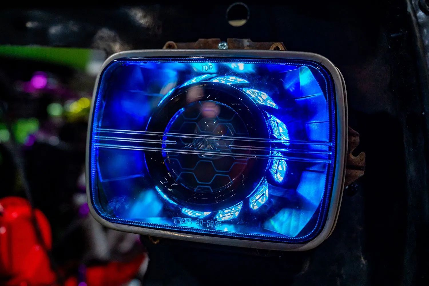 Blue-glowing, futuristic-looking vehicle headlight with a hexagonal pattern at the center.
