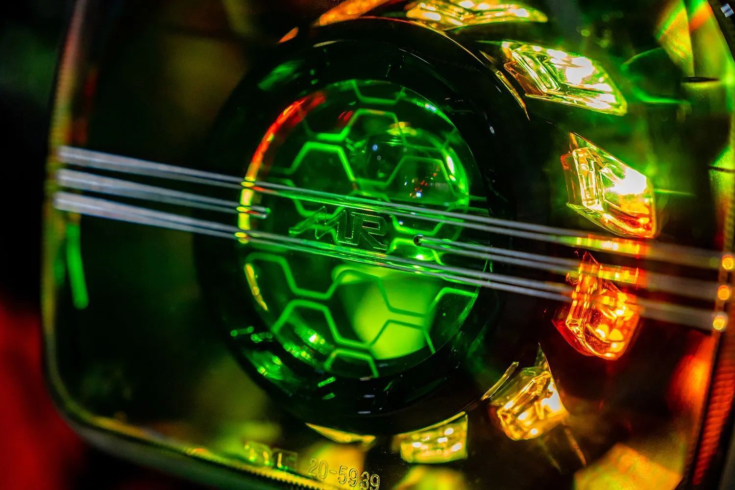 Glowing green hexagonal patterned car headlight, surrounded by amber and yellow lights.
