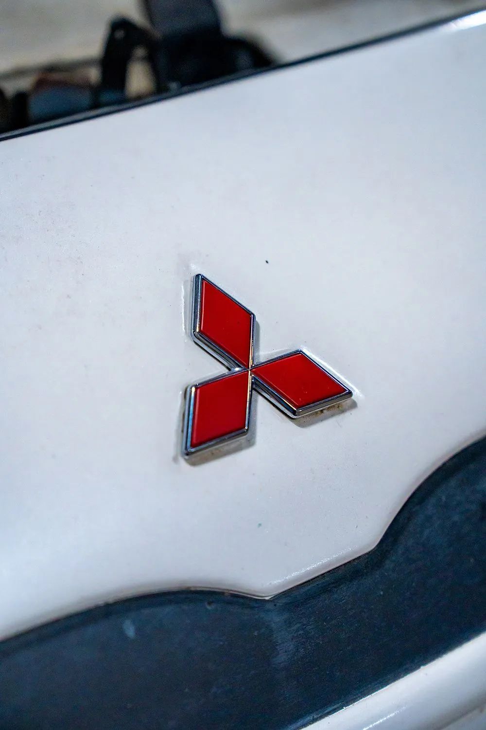 Mitsubishi logo in red and silver on a white car.