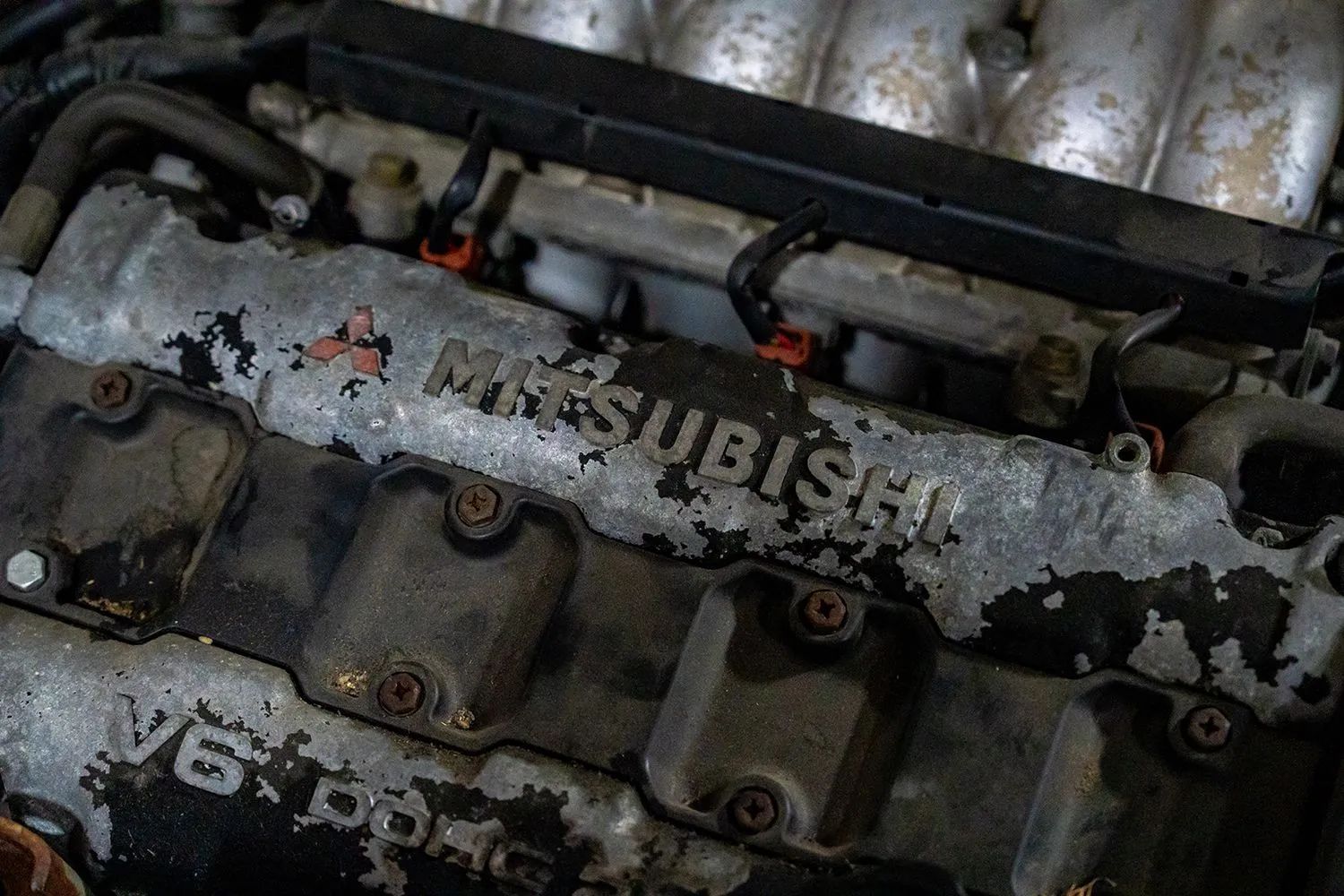 Close-up of a Mitsubishi engine with worn paint, showing the brand name and 