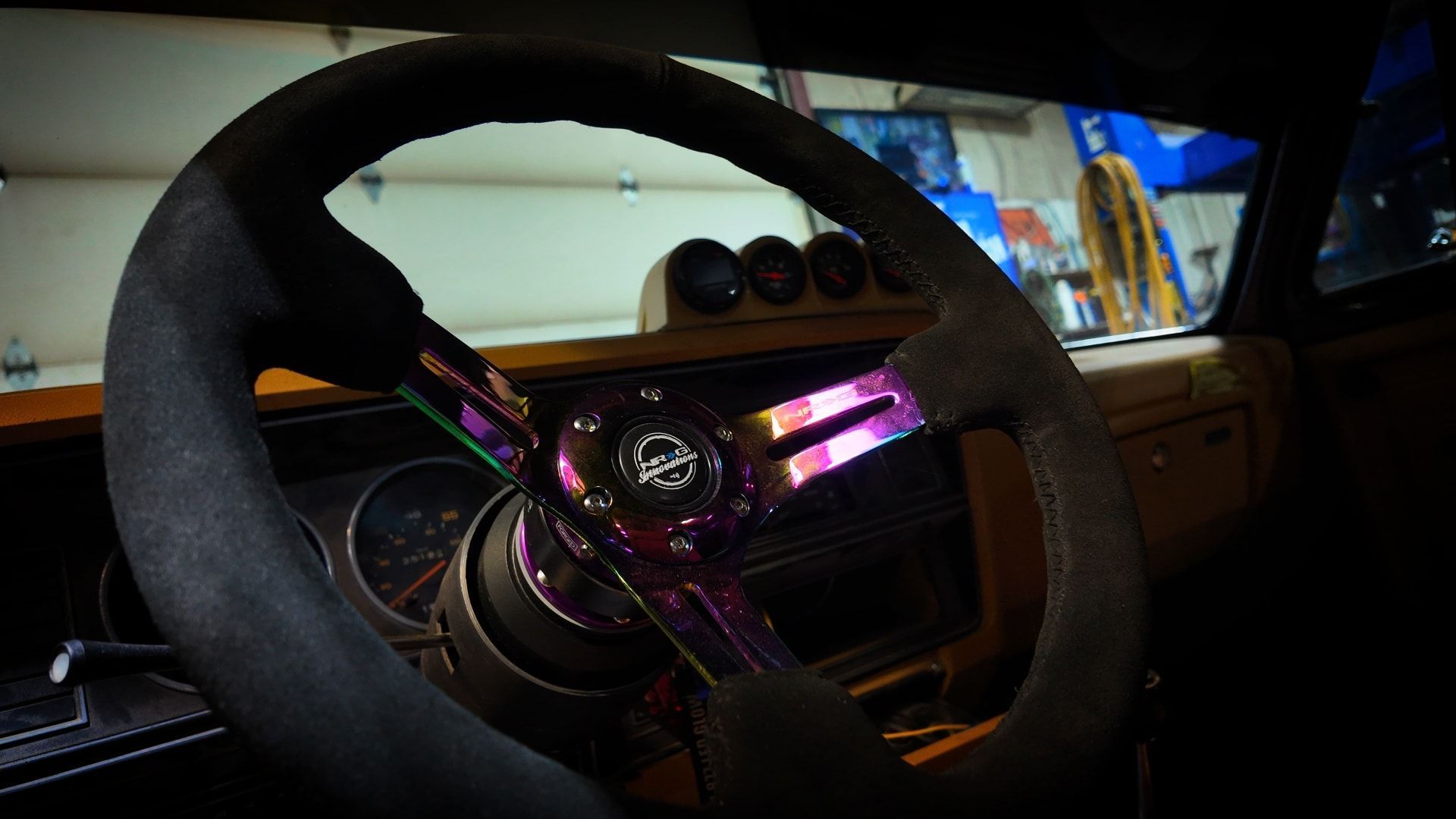 Steering wheel with a vibrant, iridescent center in a car's interior; gauges visible.