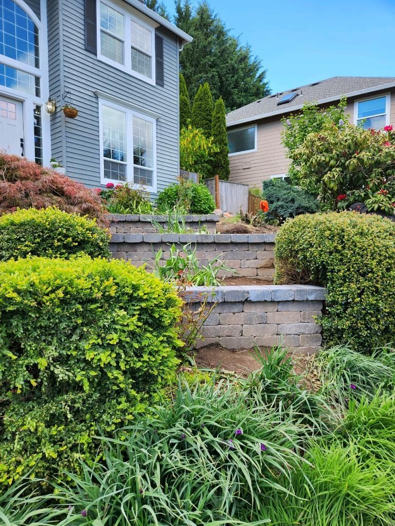 House with a gray exterior and tiered garden beds filled with greenery and flowers.