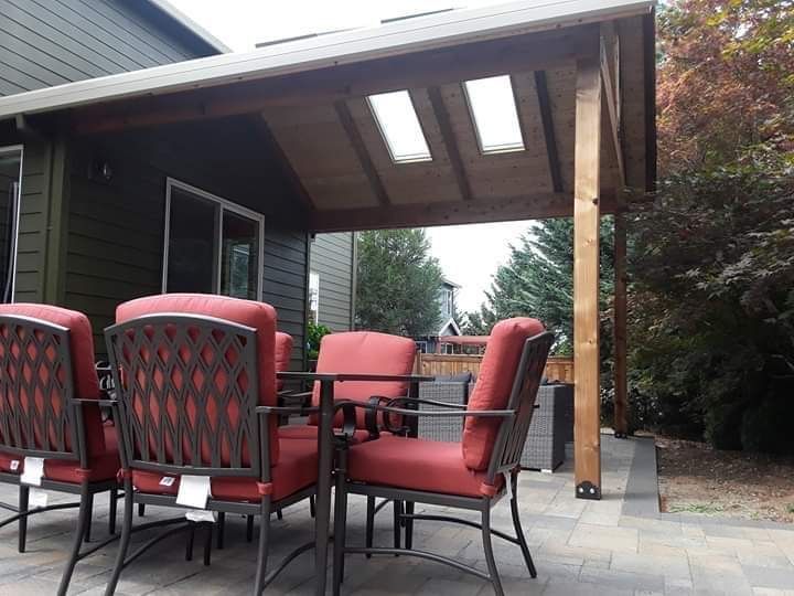 Patio with red chairs, table, and wooden pergola with skylights.