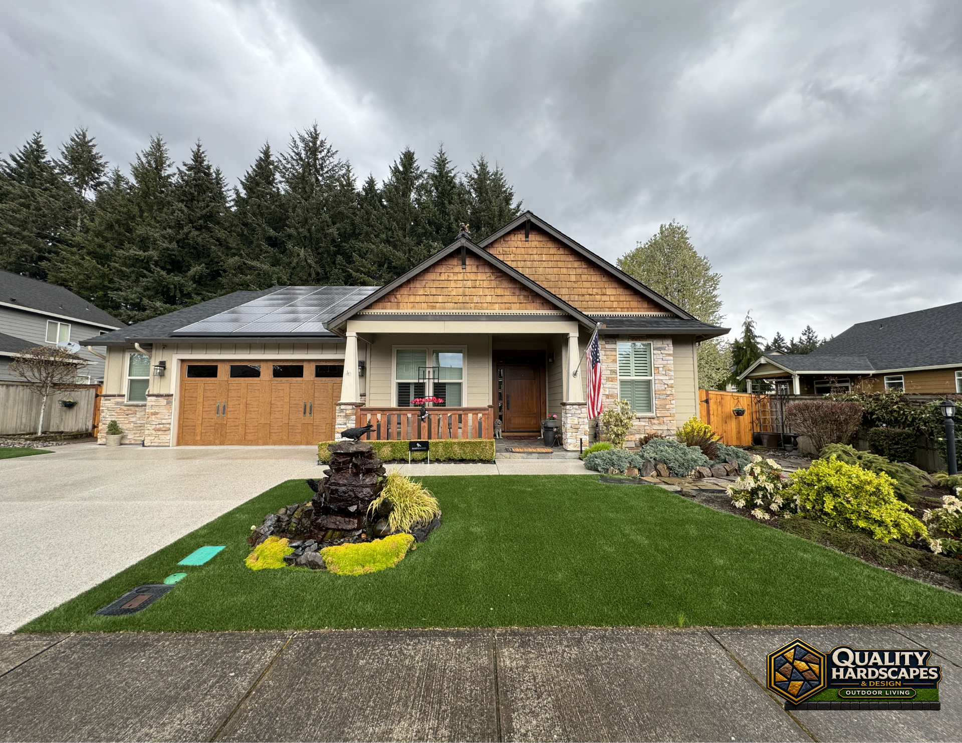 Suburban single-story house with stone exterior, double garage, porch, and landscaped front yard under cloudy skies