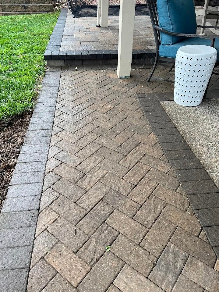 Brick patio with herringbone pattern, bordered by darker bricks, leading to a seating area.
