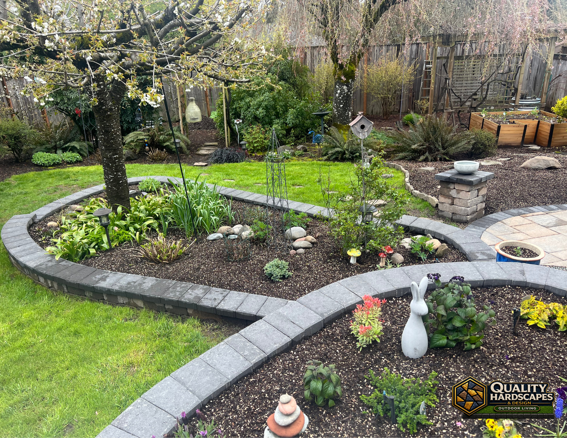 Curved stone garden beds with spring flowers and trimmed lawn in a landscaped yard