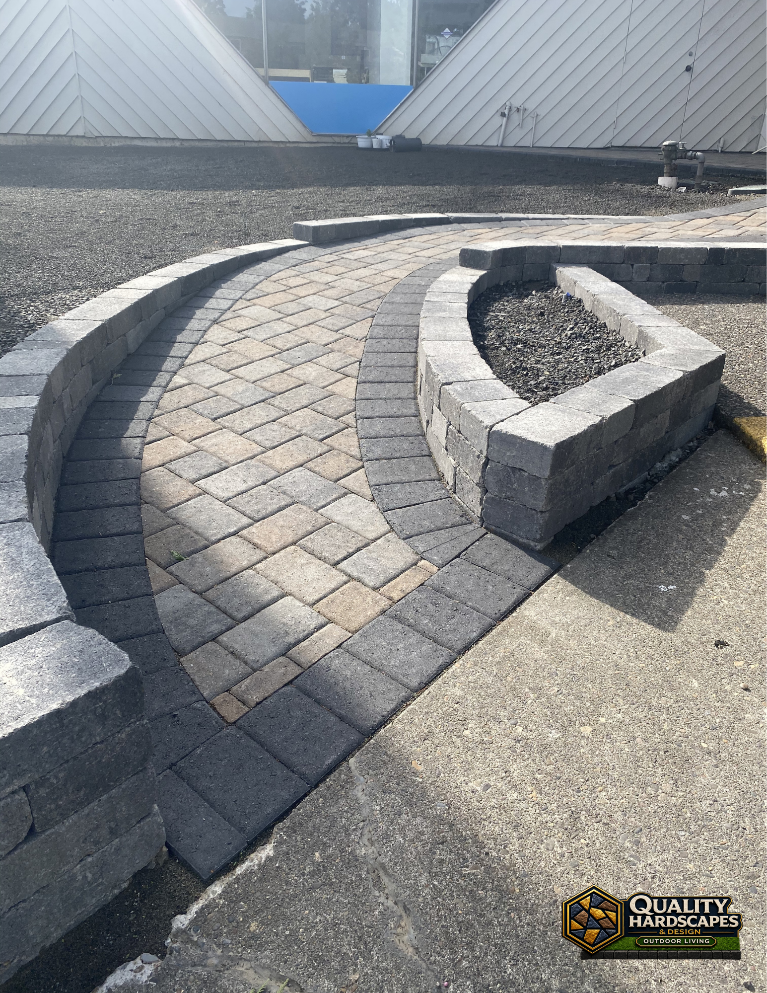 Curved brick walkway beside a raised concrete planter in a rooftop courtyard