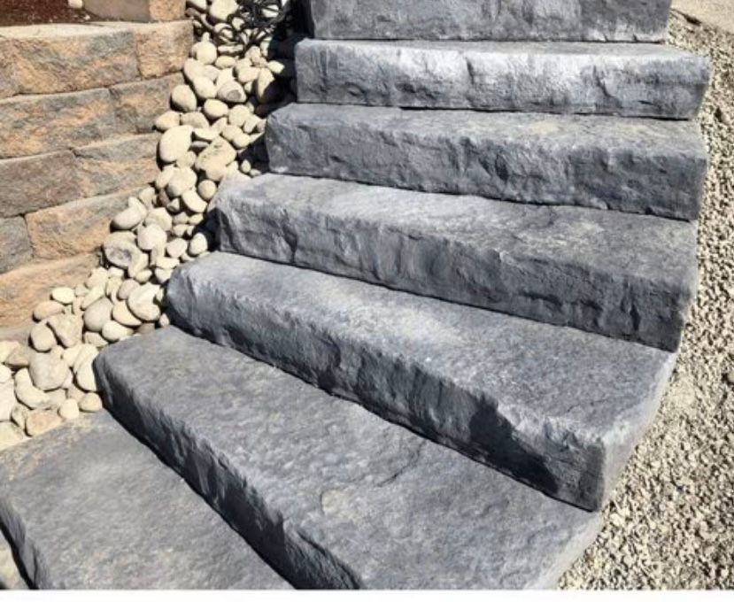 Stone steps leading up, next to a rock wall and gravel.