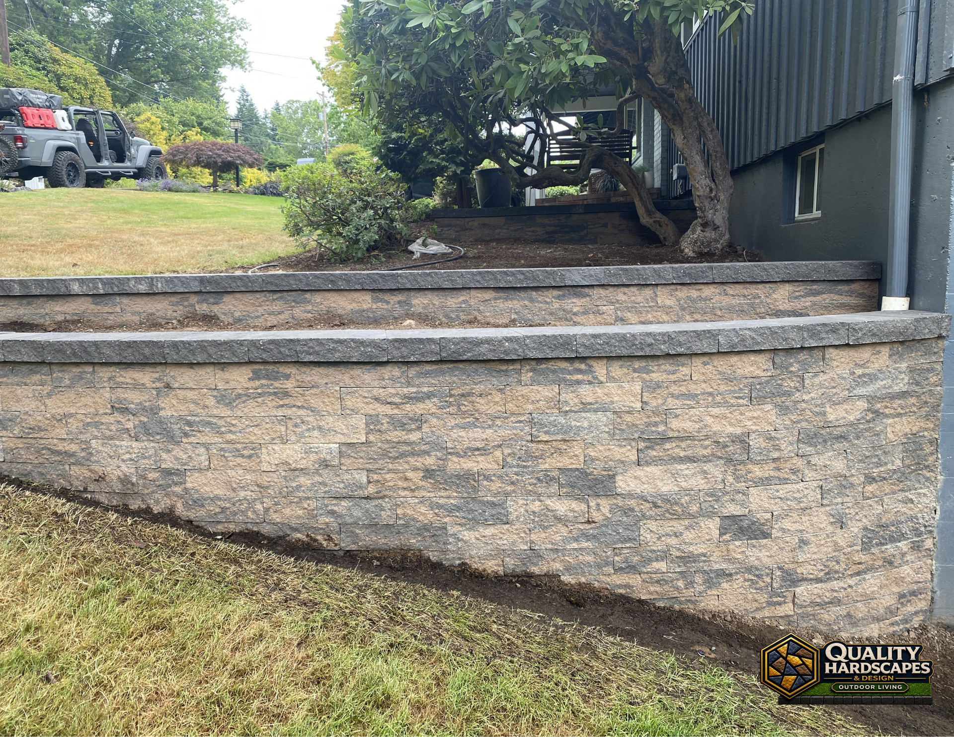 Stone retaining wall with steps and landscaped yard beside a house