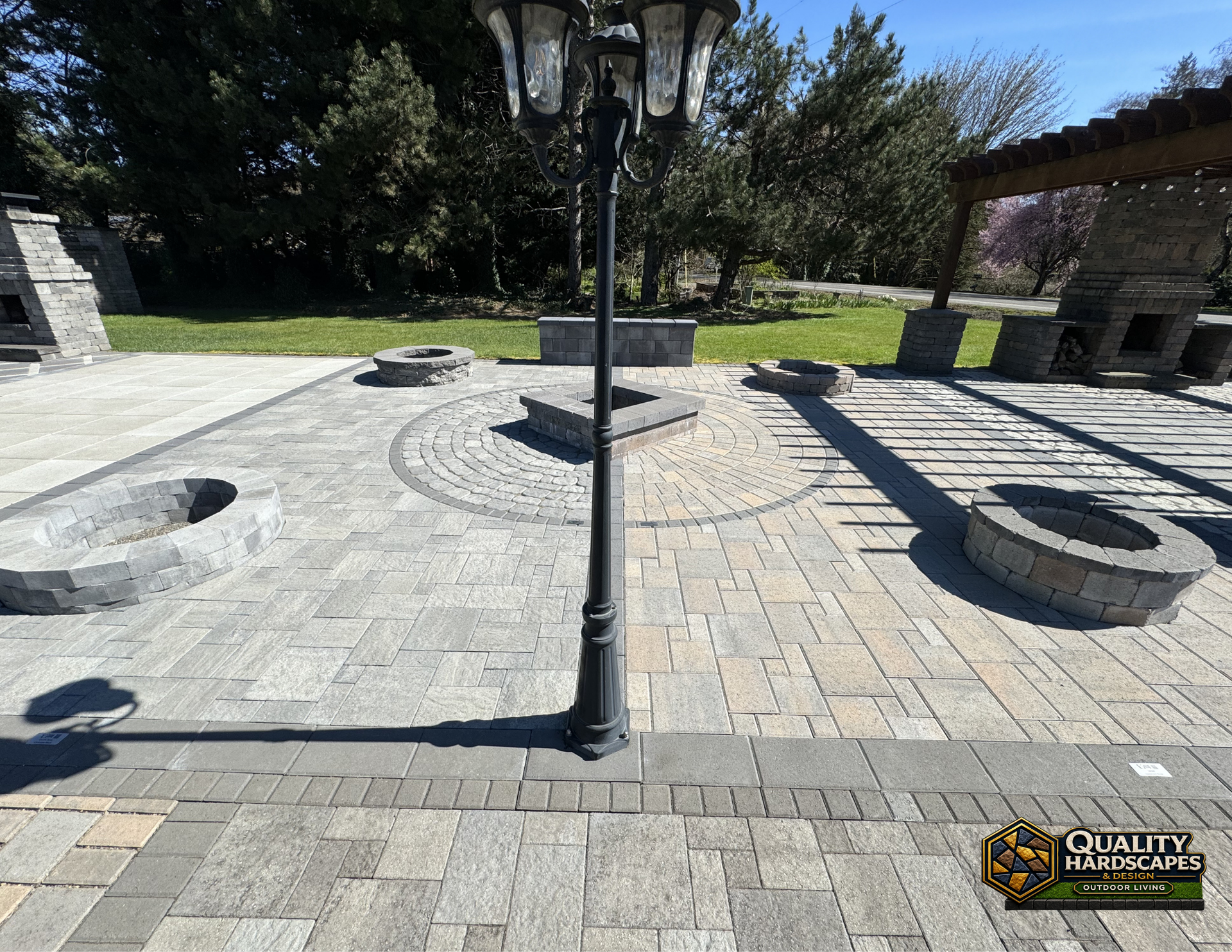 Outdoor stone plaza with circular planters and a black lamp post in sunlight