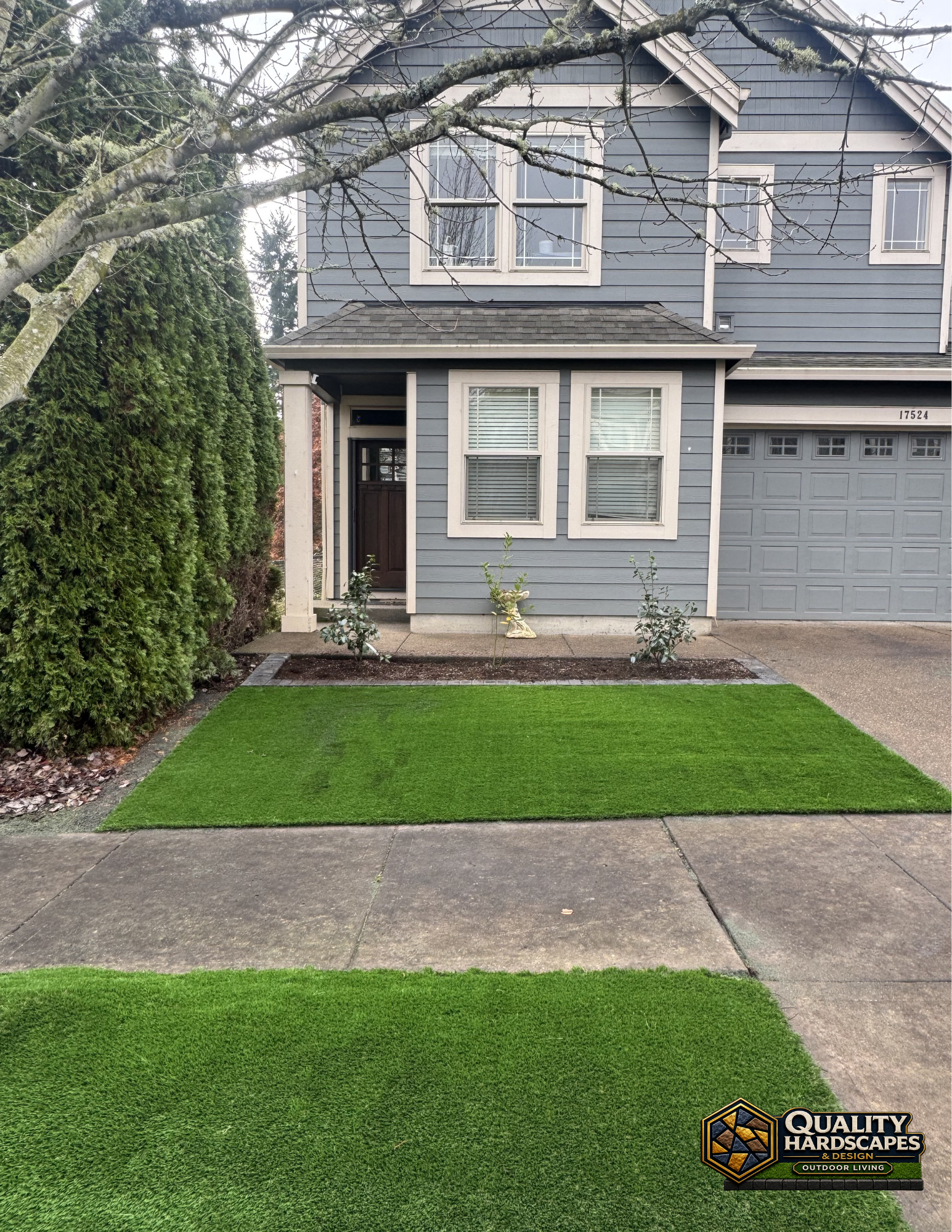 Suburban house exterior with gray siding, garage, front porch, and green lawn in front of a concrete walkway