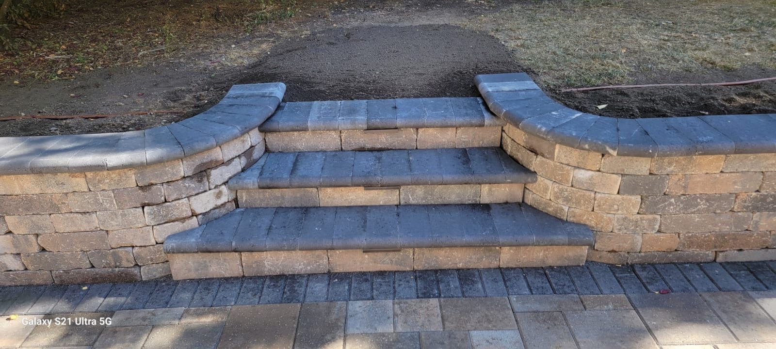Stone steps with curved retaining walls, leading up to a grassy area.