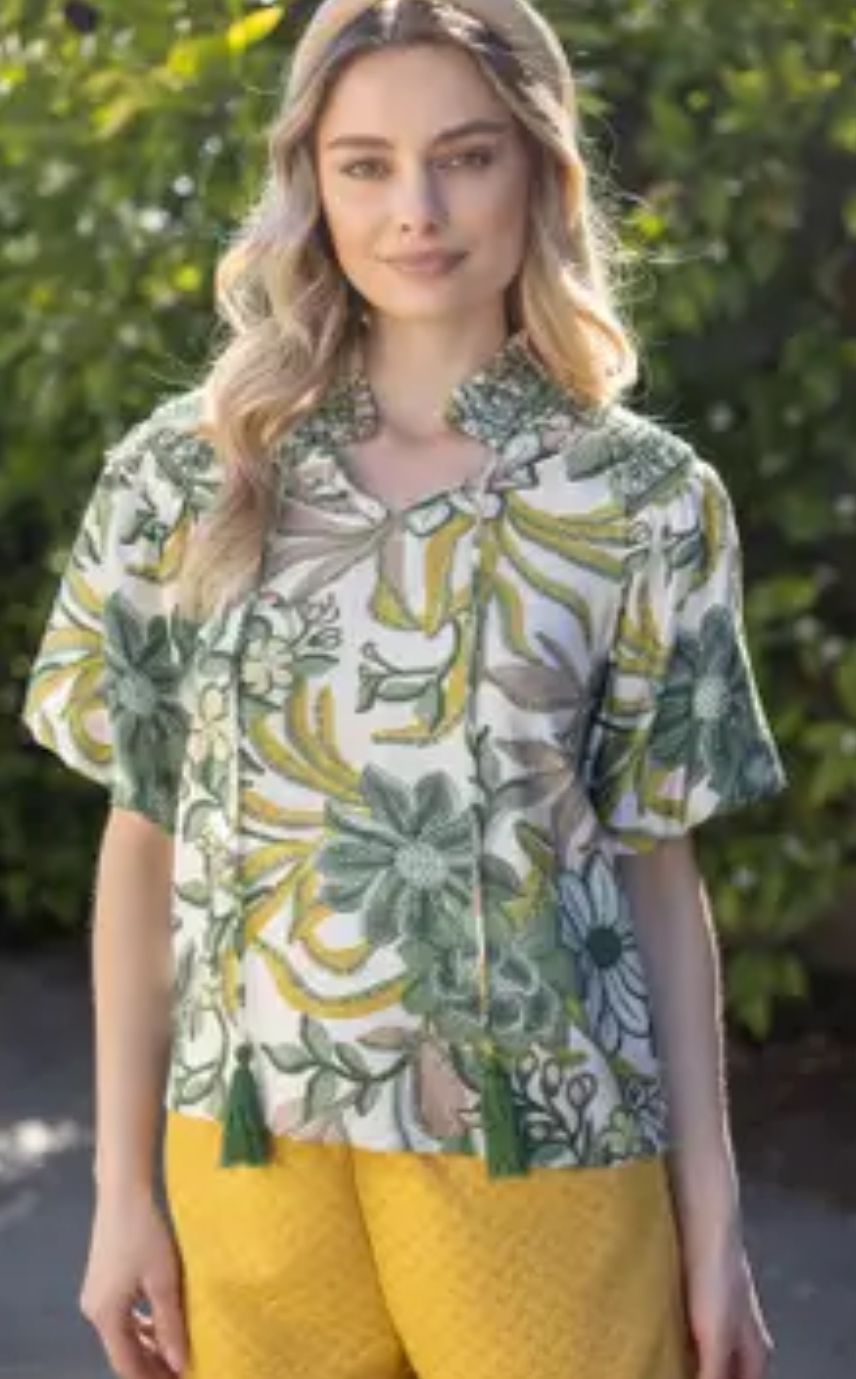 A woman is wearing a floral shirt and yellow shorts.