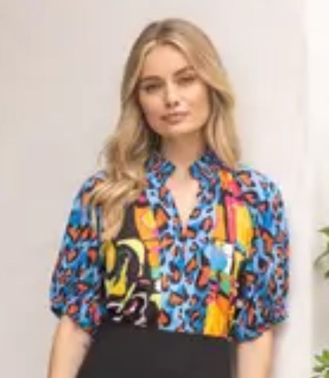 A woman is wearing a colorful shirt and a black skirt.