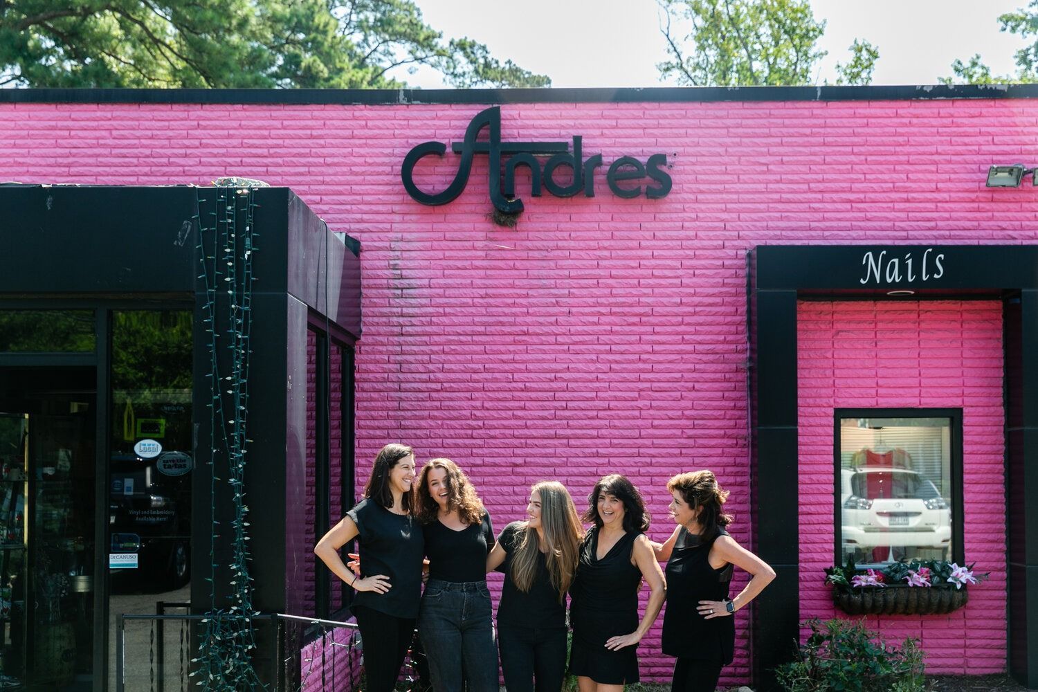 A group of women are standing in front of a pink brick building.