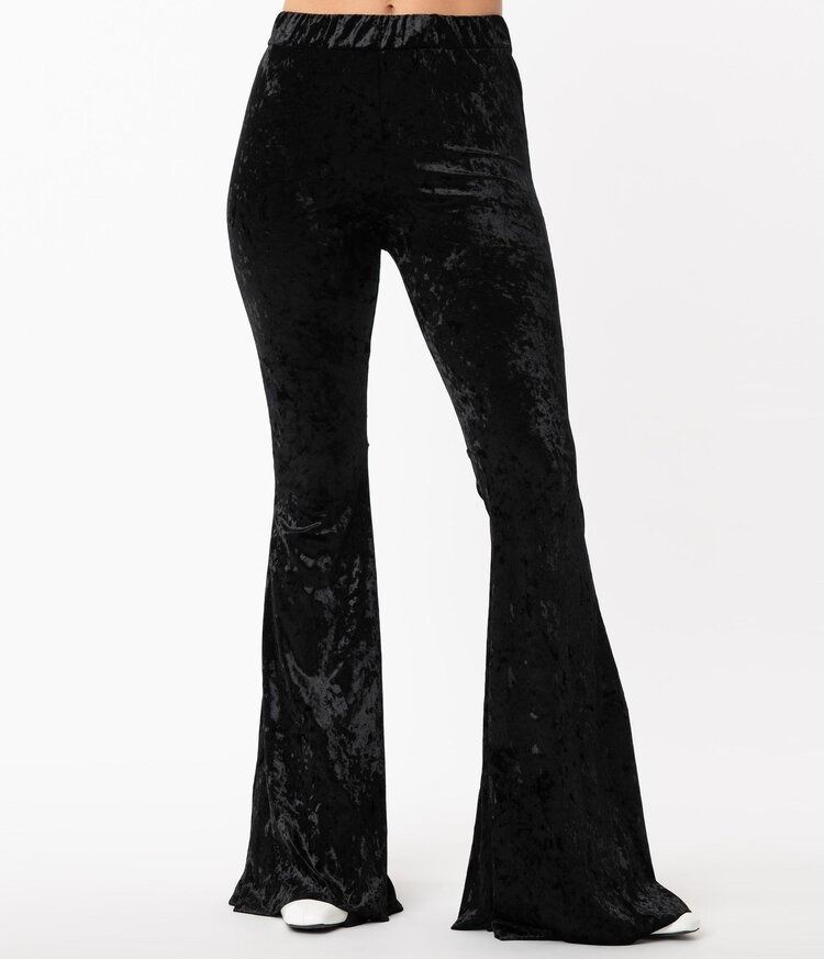 A woman is wearing a pair of black velvet flared pants