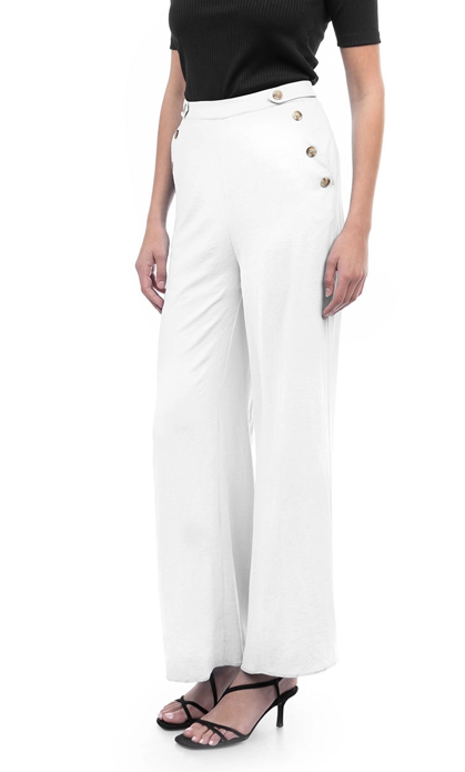 Woman in white high-waisted pants with gold buttons, black top, and sandals.
